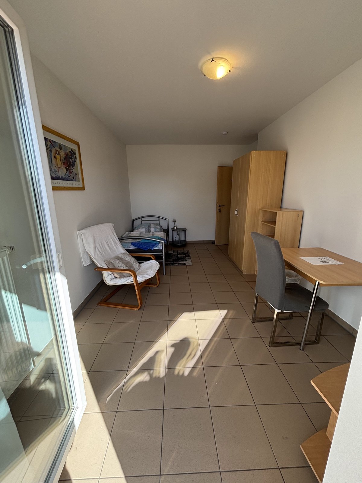 Einzelzimmer mit Schreibtisch, Bürostuhl und Sessel